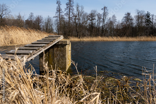 A wooden pier leading to the drainage of disused fish ponds. Taken on a sunny day, the object against the blue sky.