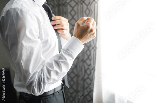 a man straightens his tie in a hotel room