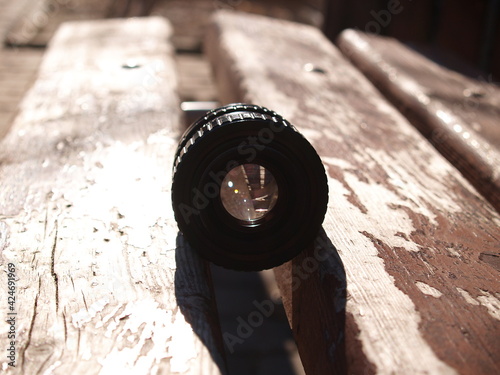 close up photo of old camera lens over wooden table. image is retro filtered. selective focus