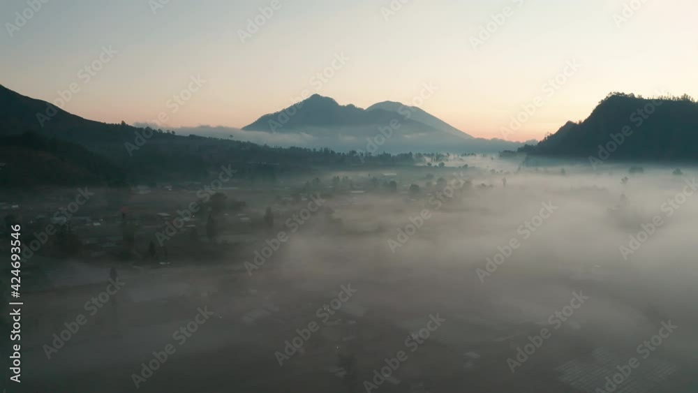 Early morning low lying fog blankets a farmland valley. Moody and atmospheric aerial shot. Early morning low lying fog blankets a farmland valley. Moody and atmospheric aerial shot.