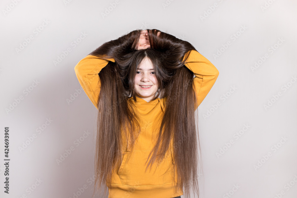A 12-year-old teenage girl with very long natural hair smiles. Horizontal banner with a place for text copy space. Children's hairdresser, haircut, hairstyles for long hair in children A 12-year-old teenage girl with very long natural hair smiles. Horizontal banner with a place for text copy space. Children's hairdresser, haircut, hairstyles for long hair in children