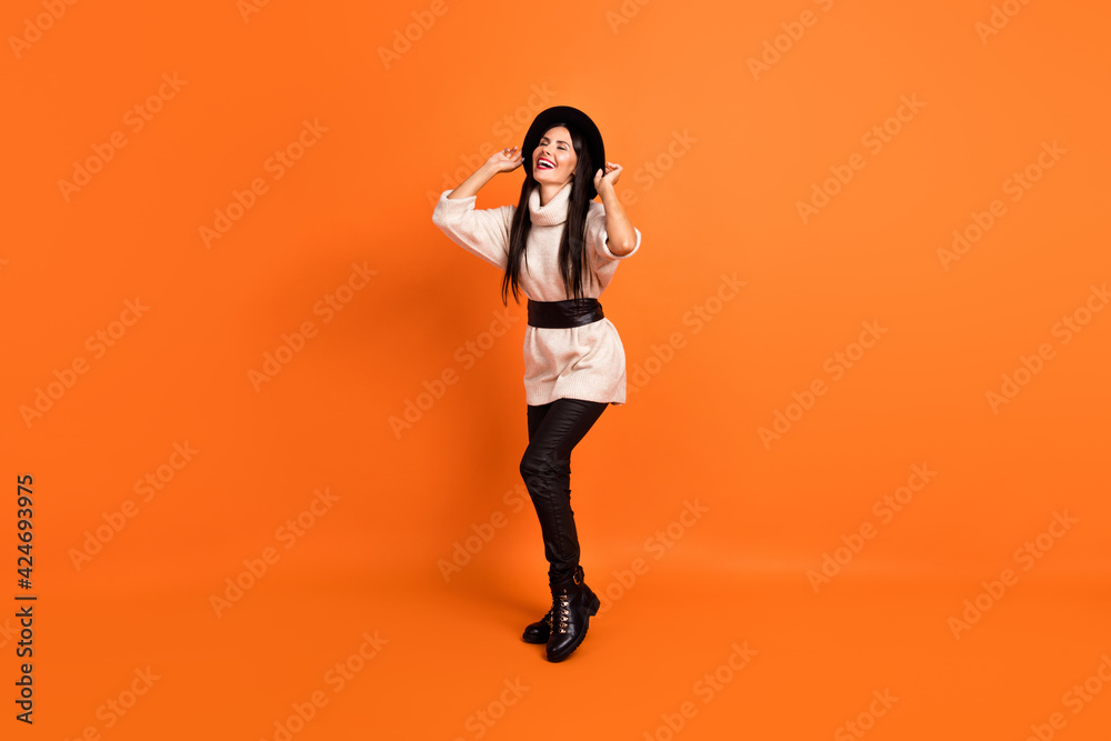 Full size photo of young gorgeous beautiful smiling dreamy funky woman dancing isolated on orange color background Full size photo of young gorgeous beautiful smiling dreamy funky woman dancing isolated on orange color background