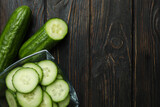 Bowl with ripe cucumbers on wooden background