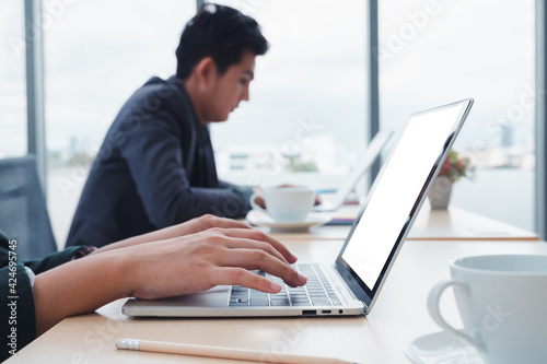 Businessman working at a home office uses a close-up keyboard, a man sitting on a wooden table and using a contemporary laptop by the window. Concept of close-up of a hand printed on a laptop.