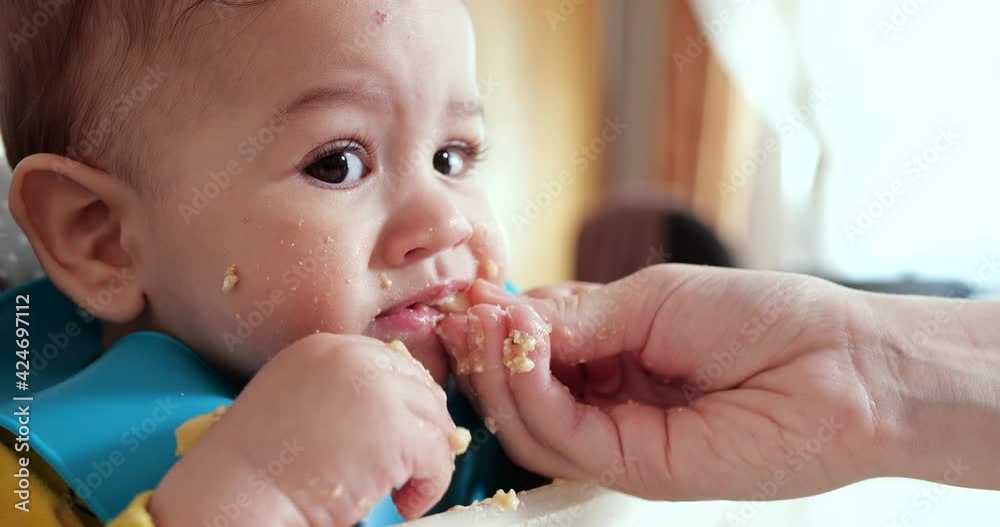 mother holds the baby in her arms and feeds her boy with a spoon. family, food, child, eating and parenthood concept mother holds the baby in her arms and feeds her boy with a spoon. family, food, child, eating and parenthood concept