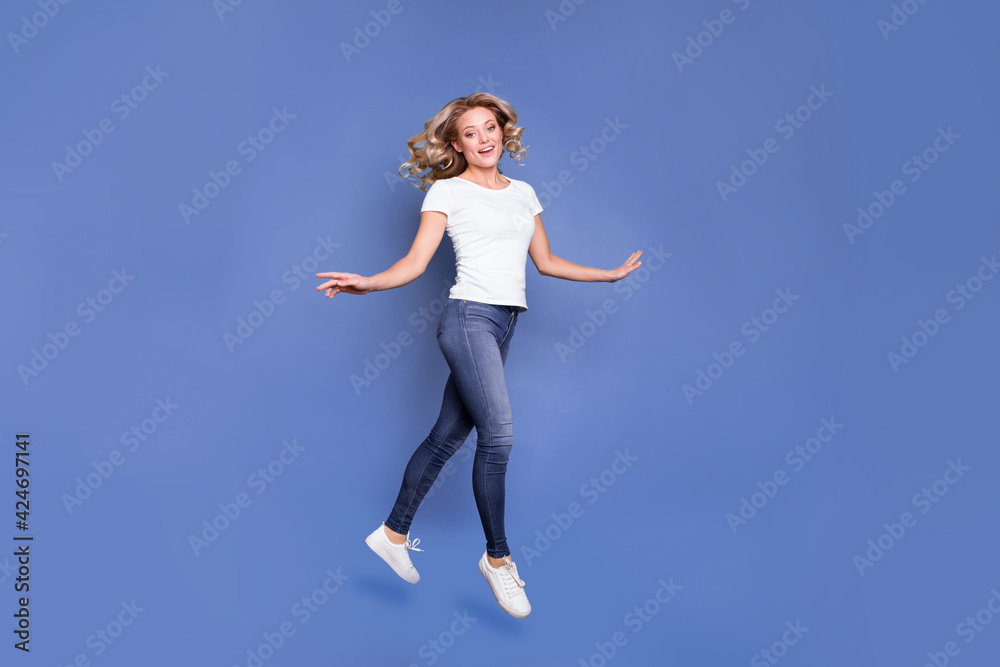 Full length body size view of attractive cheerful wavy-haired girl jumping walking good mood isolated over blue color background Full length body size view of attractive cheerful wavy-haired girl jumping walking good mood isolated over blue color background