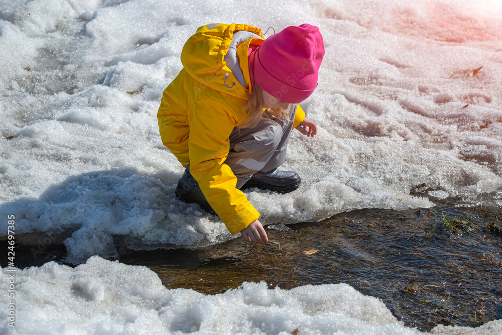a little girl in a yellow jacket plays by the stream a little girl in a yellow jacket plays by the stream