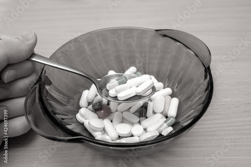A lot of medicine in black bowl with spoon. Eating drugs concept