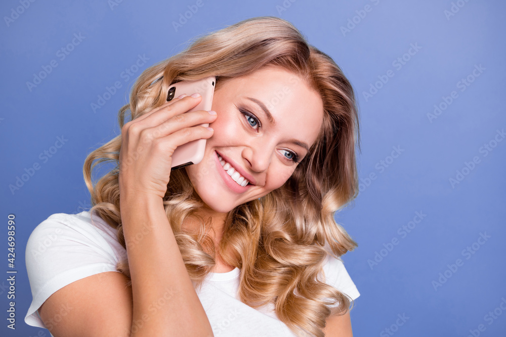 Close-up portrait of attractive cheerful wavy-haired girl talking on phone enjoying isolated over blue color background Close-up portrait of attractive cheerful wavy-haired girl talking on phone enjoying isolated over blue color background