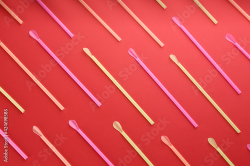Colorful plastic drinking straws on red background, flat lay © New Africa