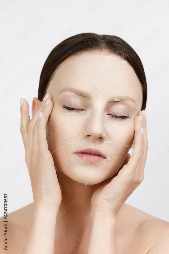 Face Skin Care moisturizing Korean cosmetics concept. Portrait Of Beautiful woman applying and smoothing White Sheet Mask Face Skin Care moisturizing Korean cosmetics concept. Portrait Of Beautiful woman applying and smoothing White Sheet Mask