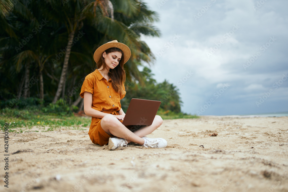 woman freelancer on the island on the sand near the sea and trees in the background