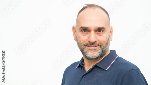 Portrait of a middle aged man in a blue polo on a light background. © A Stock Studio