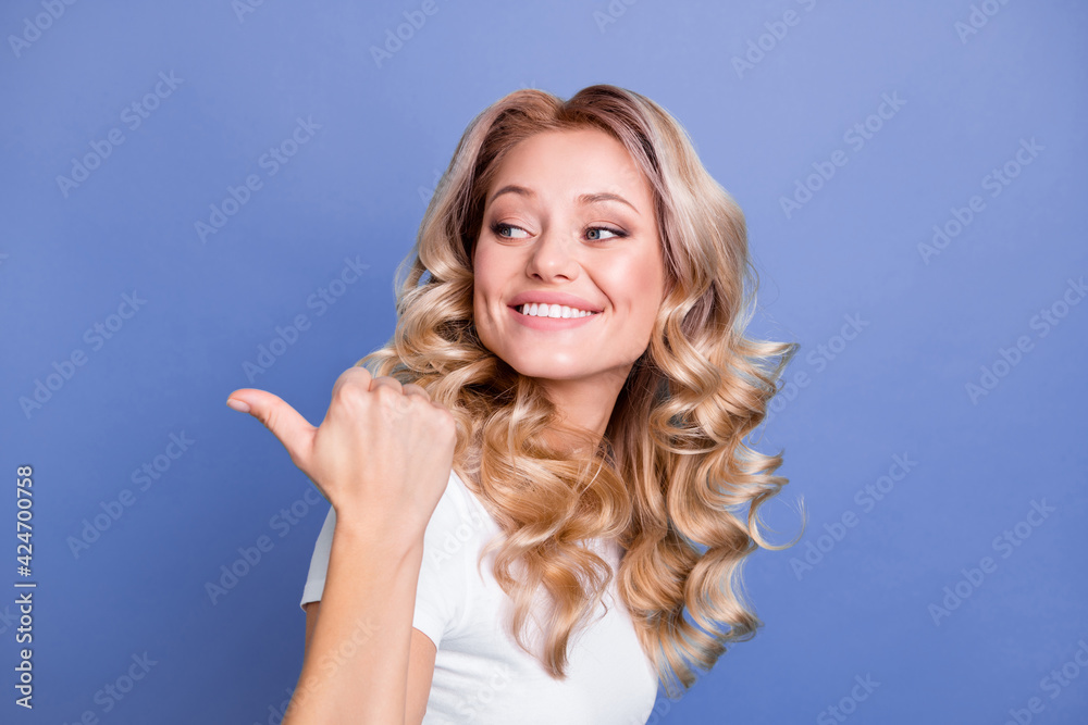 Fototapeta premium Photo of young lovely pretty smiling happy girl look point thumb copyspace recommendation isolated on blue color background