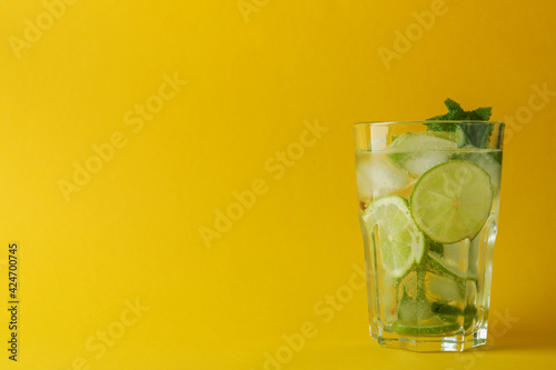 Glass of mojito cocktail on yellow background