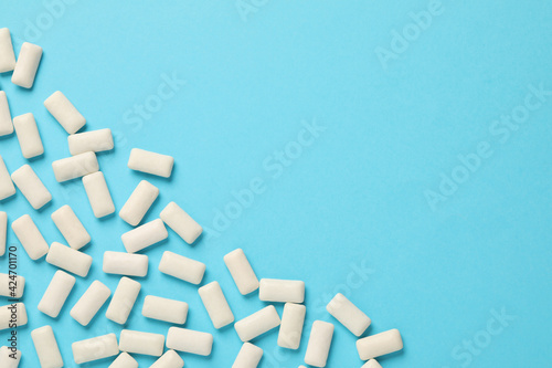 Many chewing gum pieces on light blue background, flat lay. Space for text