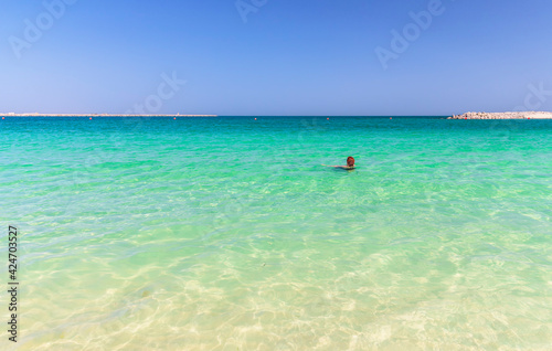 Girl swims in turquoise water on the beach