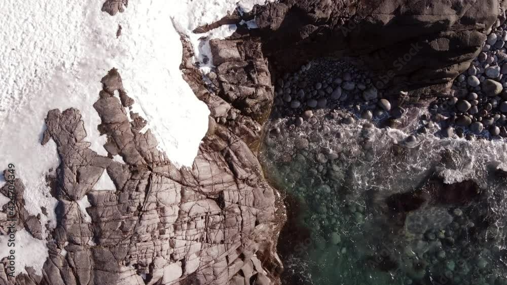 winter aerial flight top over waves rolling on artic ocean shore with round stones, ocean waves at storm winter aerial flight top over waves rolling on artic ocean shore with round stones, ocean waves at storm