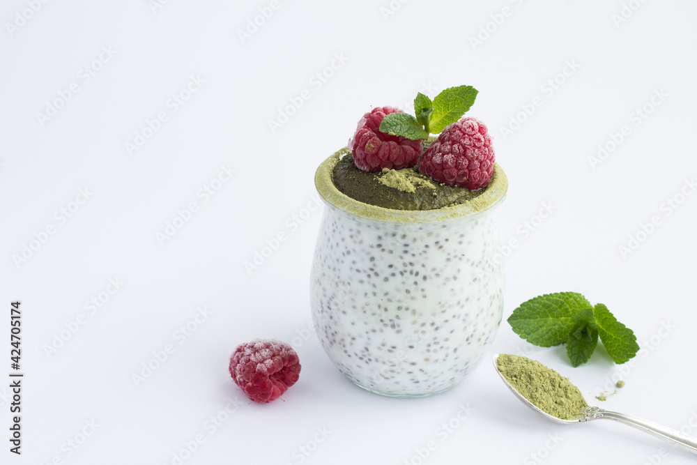 Chia seed pudding with raspberry and matcha tea in the glass jar on the white background. Close-up. Copy space. Chia seed pudding with raspberry and matcha tea in the glass jar on the white background. Close-up. Copy space.