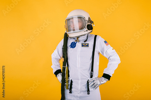 Canvas-taulu Male cosmonaut in space suit and helmet with foggy glass, arms at waist, on yellow background
