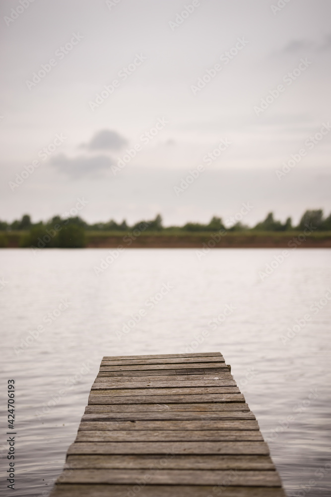 Evening view of the wooden fishing bridge for fishing. Empty boat dock on a river or lake.