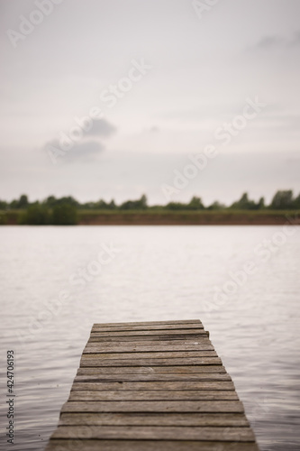 Evening view of the wooden fishing bridge for fishing. Empty boat dock on a river or lake.