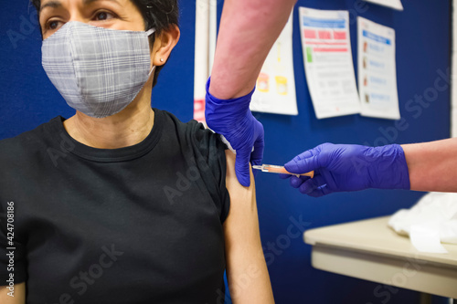 Asian woman getting Covid 19 vaccine injection, UK photo