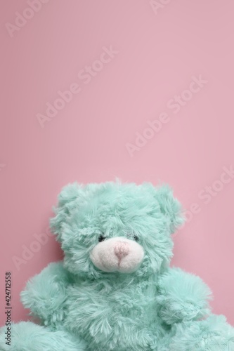 A cute mint colored teddy bear on a baby pink vertical background. Sweet kids background picture in pastel colors