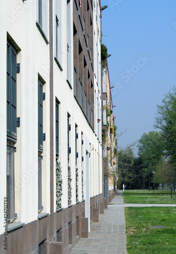 Facciata laterale di palazzo con prato alberi e cielo