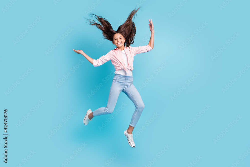 Full size photo of energetic cheerful school person jumping hair flying good mood isolated on blue color background Full size photo of energetic cheerful school person jumping hair flying good mood isolated on blue color background