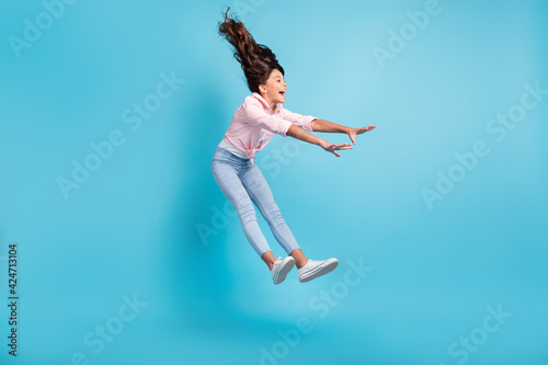 Full length photo of astonished carefree kid playing jumping falling open mouth isolated on blue color background