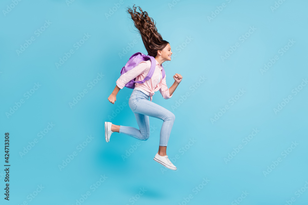 Full size profile side photo of young happy smiling cheerful girl with brown hair jump isolated on blue color background Full size profile side photo of young happy smiling cheerful girl with brown hair jump isolated on blue color background