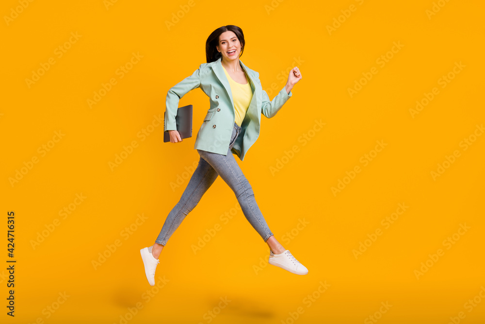 Full size photo of young lovely pretty smiling cheerful girl run jump with laptop in hand isolated on yellow color background