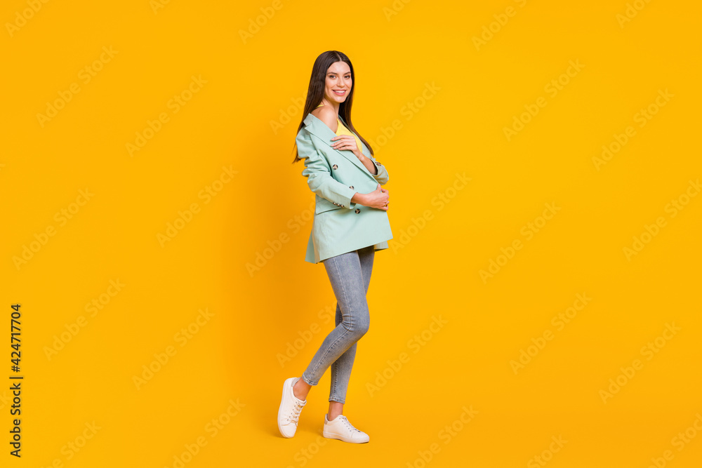 Full size photo of young smiling positive good mood lovely pretty girl showing shoulder isolated on yellow color background Full size photo of young smiling positive good mood lovely pretty girl showing shoulder isolated on yellow color background