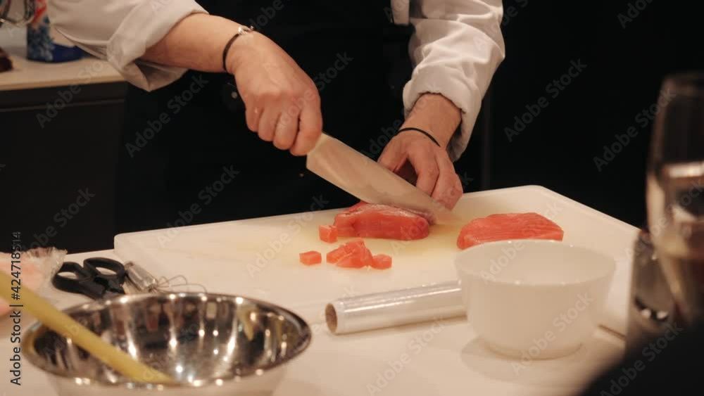 The cook cuts the cooked meat into pieces. The cook cuts the cooked meat into pieces.