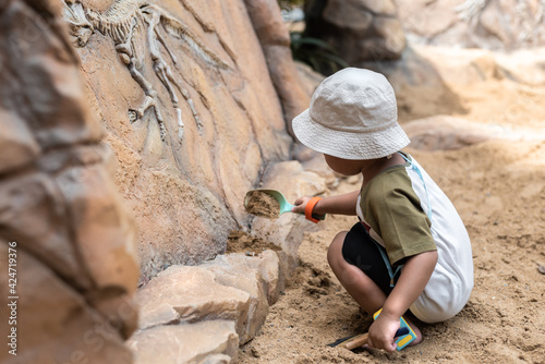 asian boy with his showel digging educational fossil dinosaur bones