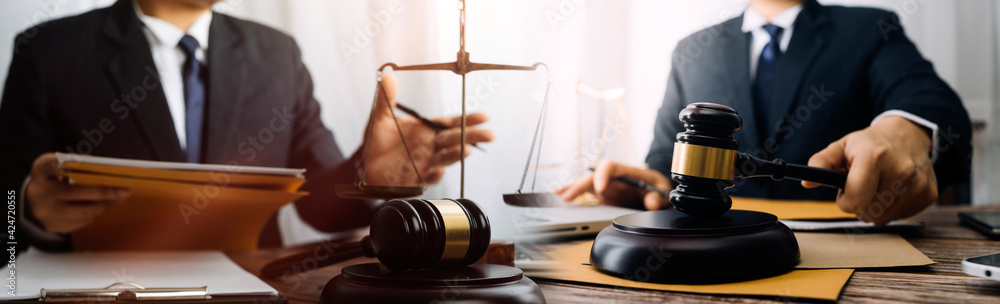 Business and lawyers discussing contract papers with brass scale on desk in office. Law, legal services, advice, justice and law concept picture with film grain effect Business and lawyers discussing contract papers with brass scale on desk in office. Law, legal services, advice, justice and law concept picture with film grain effect