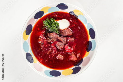 Borscht with meat in a colored plate on a white background
