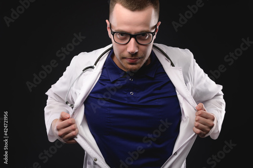 фотографія young doctor a man in glasses and a robe makes a heroic gesture like a superman