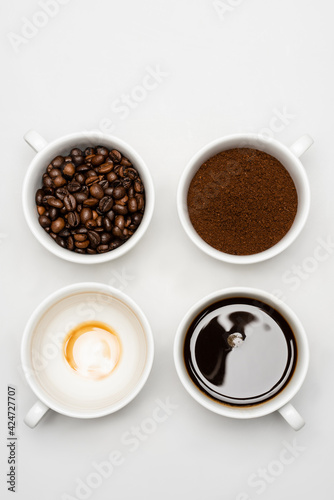 top view of prepared americano near fresh ground coffee and beans in cups on white