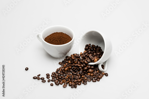 ground coffee and roasted beans in cups on white