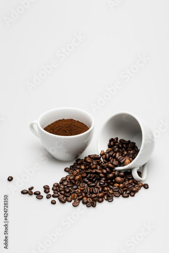 beans and ground coffee in mugs on white