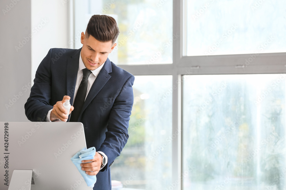 Young businessman cleaning computer in office Young businessman cleaning computer in office