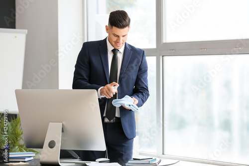 Young businessman cleaning computer in office