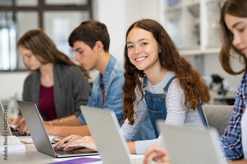 Happy high school girl using laptop in classroom - obrazy, fototapety, plakaty 