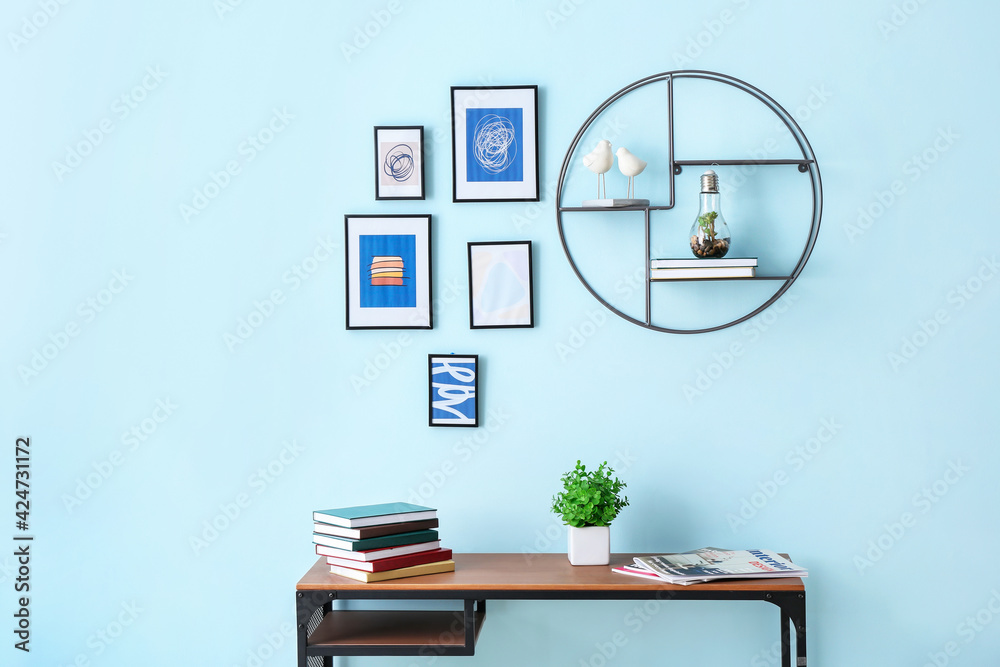 Books on table near color wall with stylish pictures - obrazy, fototapety, plakaty 