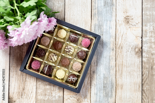 Chocolates in a box on the table. Gift wrap. Wooden background. Close-up. Place for your text. © EleniaPhoto