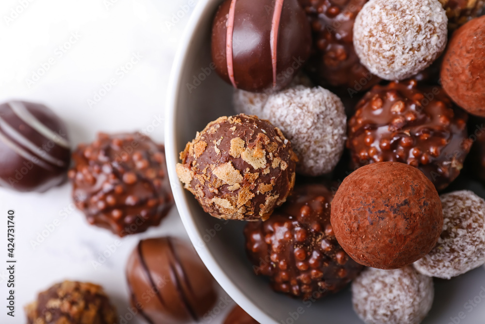 Bowl with sweet chocolate candies on light background, closeup Bowl with sweet chocolate candies on light background, closeup