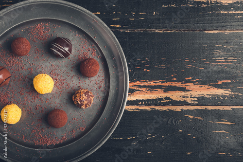 Plate with sweet chocolate candies on wooden background