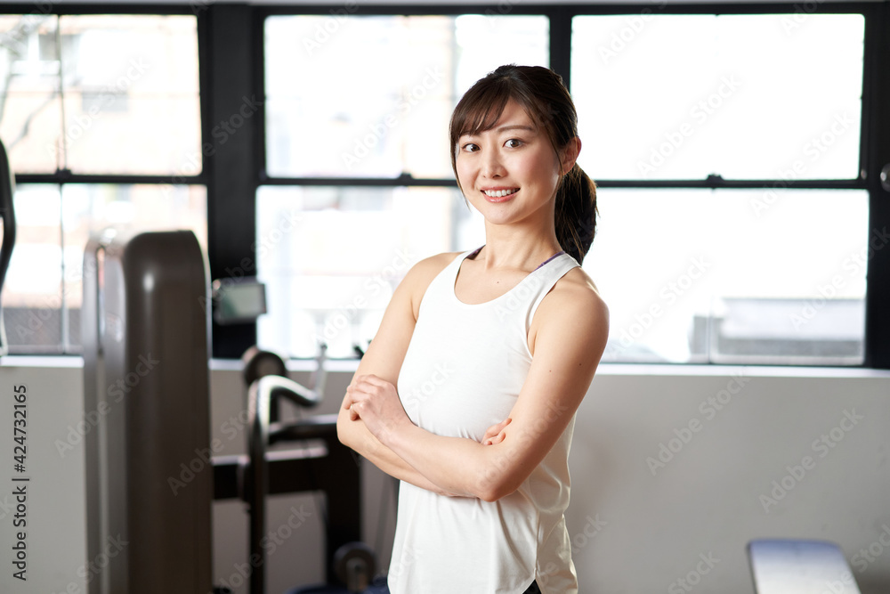 トレーニングジムで笑顔で立つアジア人女性トレーナー